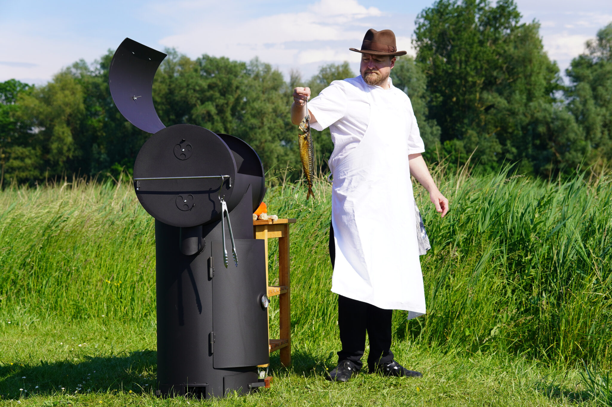 chef die een gerookte makreel vasthoudt the barrel staat open.